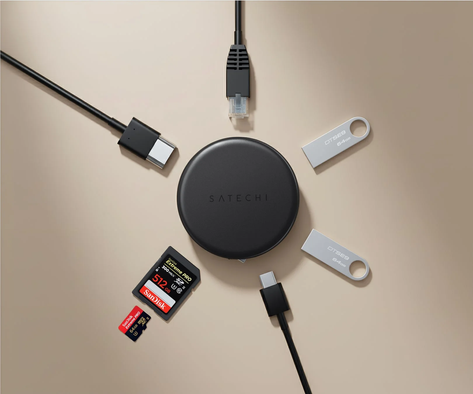 Satechiの黒いデバイスを中心に、USB-Cケーブル、イーサネットケーブル、USBメモリ、SDカードとMicroSDカードが放射状に配置された俯瞰写真