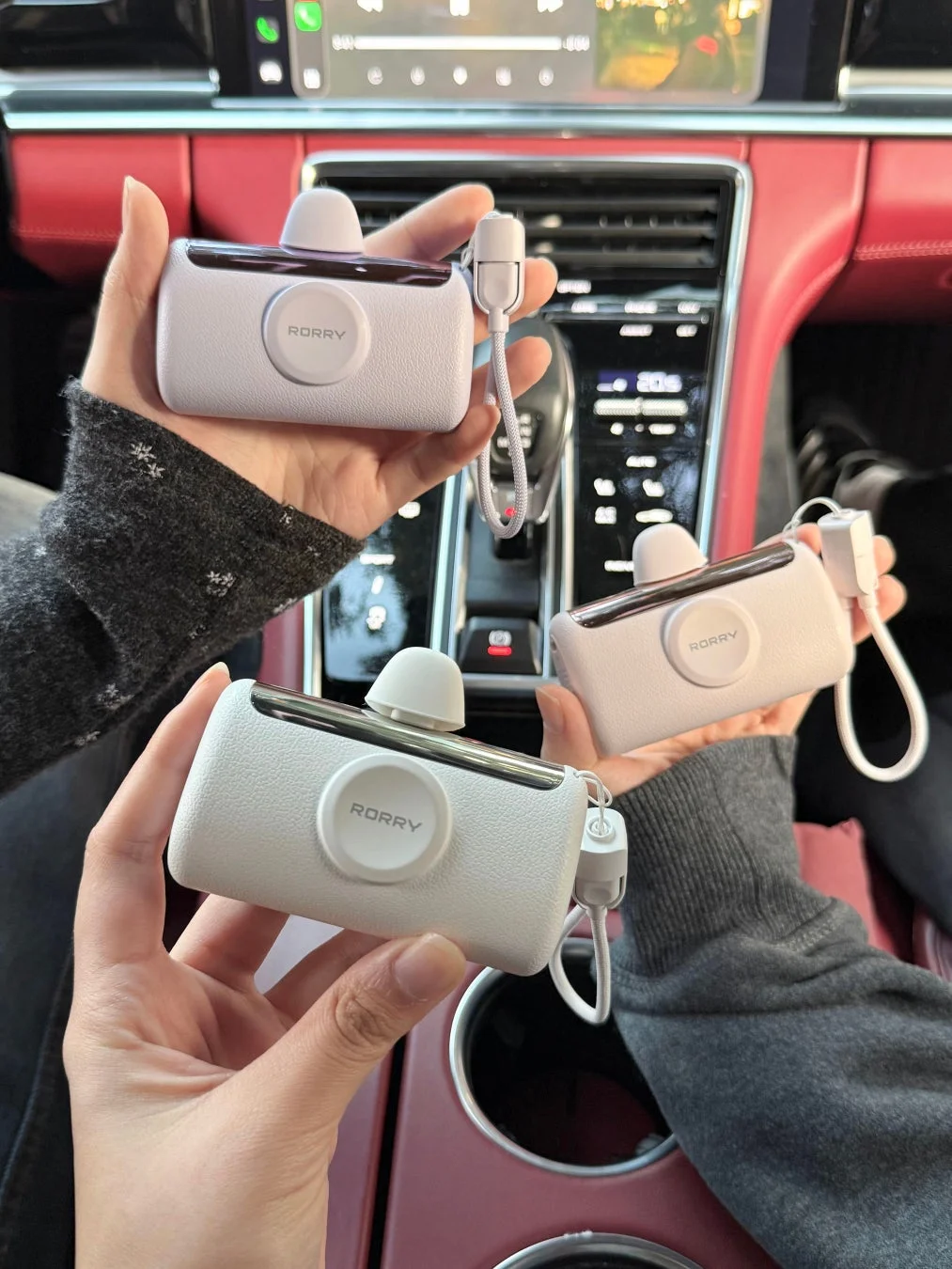 車内で「RORRY」の充電器を持つ複数の手