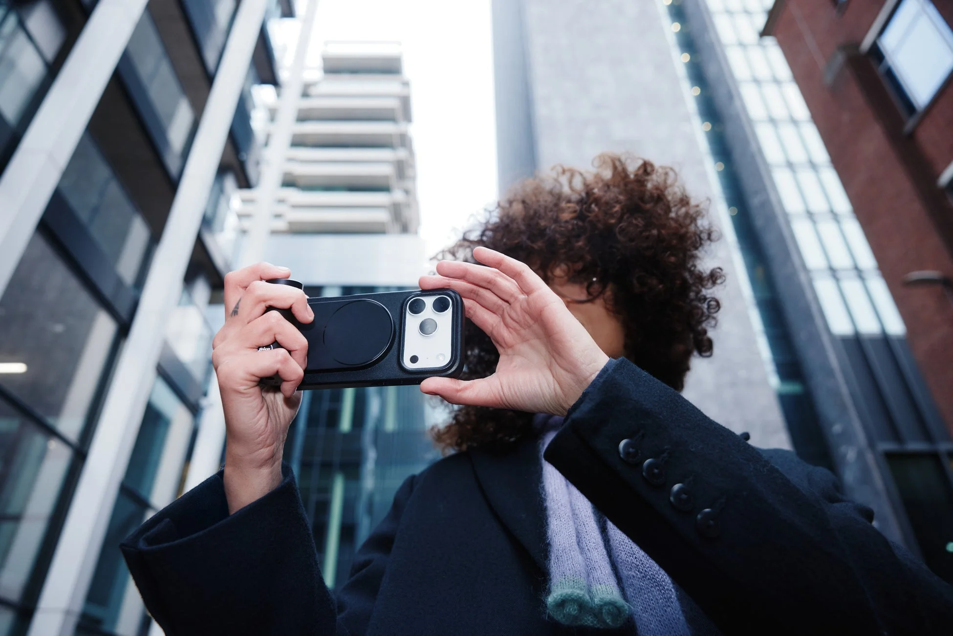 Leica LUXグリップ付きiPhoneで都会の建物を撮影する人物